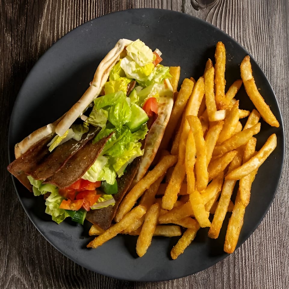 Mustard Cafe & Grill Foothill Ranch's gyro with meat, lettuce, tomatoes, and fries on a dark plate.